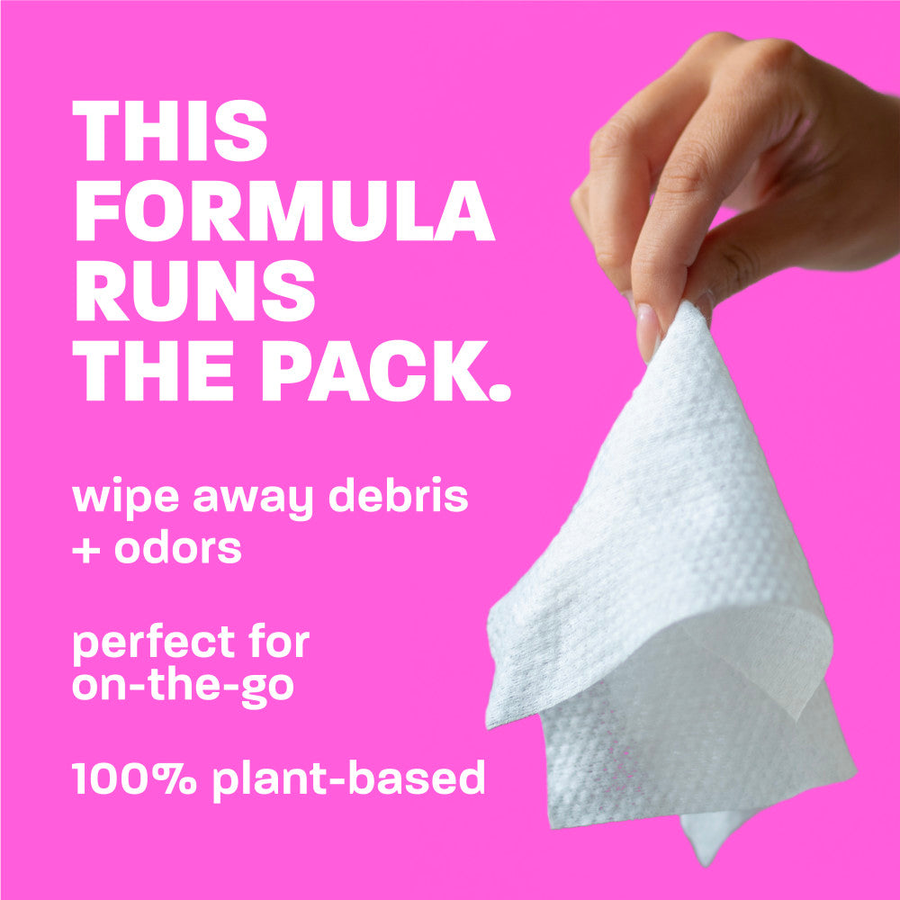 Hand holding a white wipe against a pink background with text about the product's benefits.