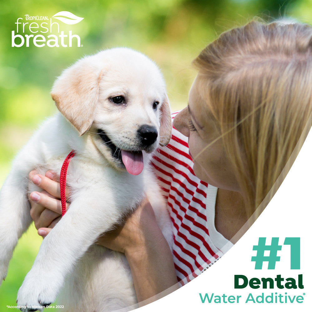 Woman holding a puppy with 'TropiClean fresh breath' branding and text about dental water additive.