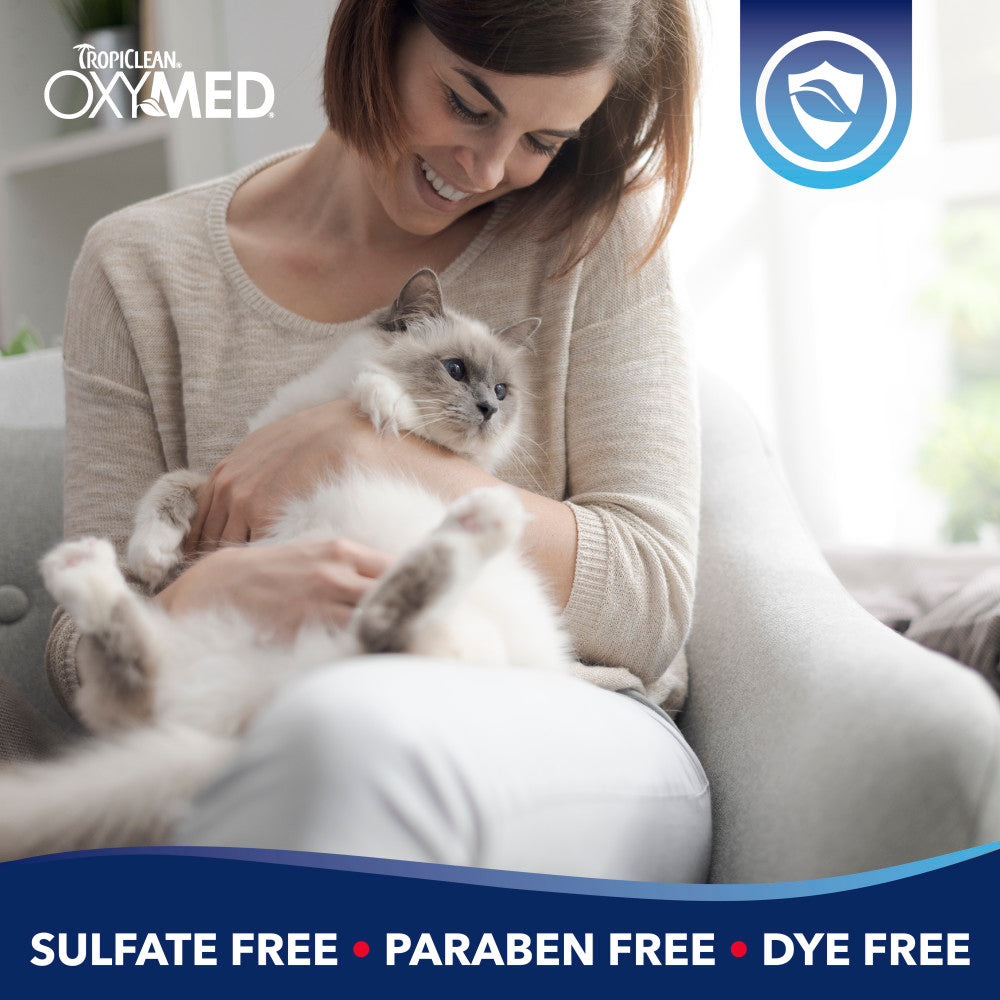 Woman holding a cat with Tropiclean OxyMed branding and product benefits text.