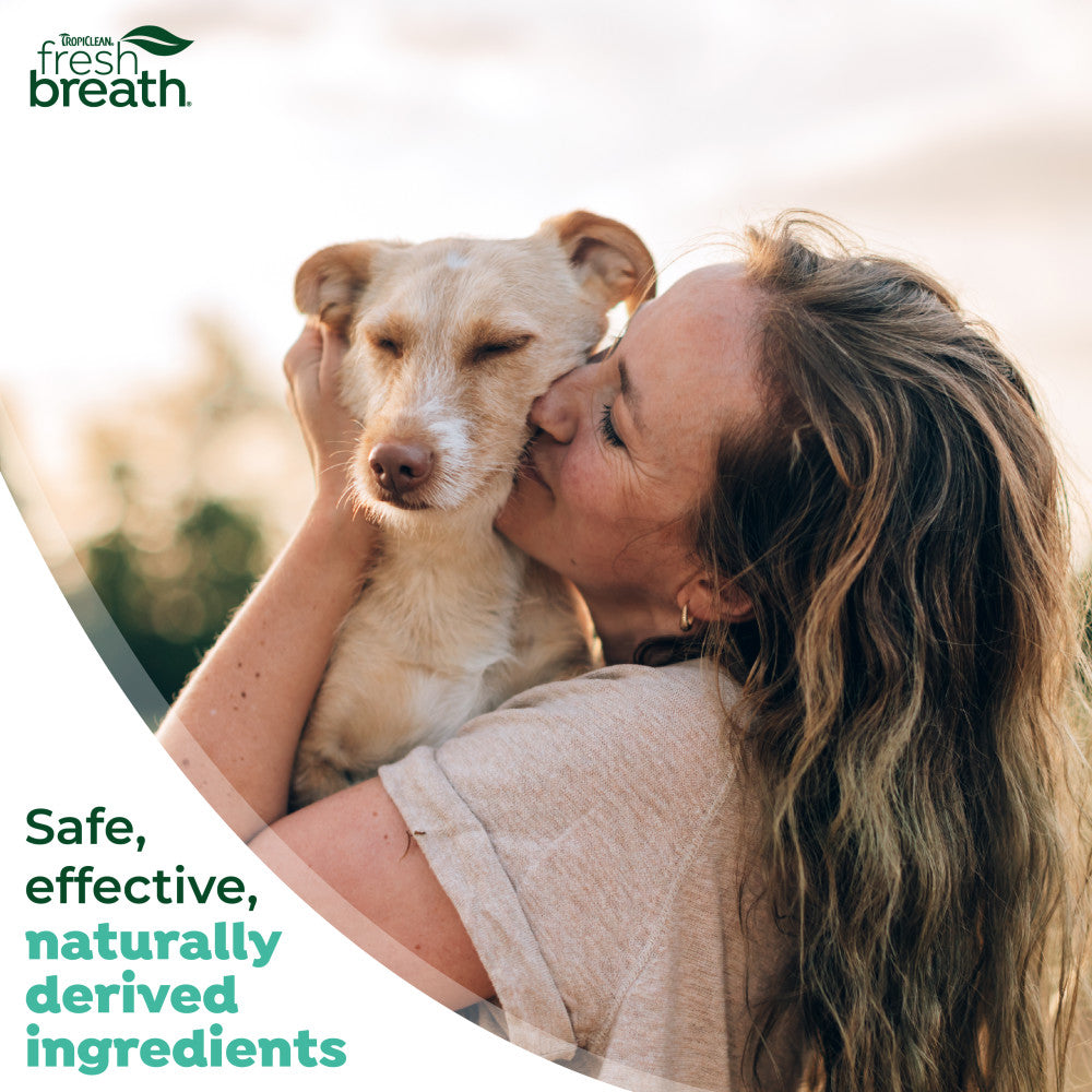 Fresh Breath Enticers Smoked Beef Brisket Oral Care Kit. Woman kissing a dog with 'TropiClean Fresh Breath' logo and text about safe, effective, naturally derived ingredients.