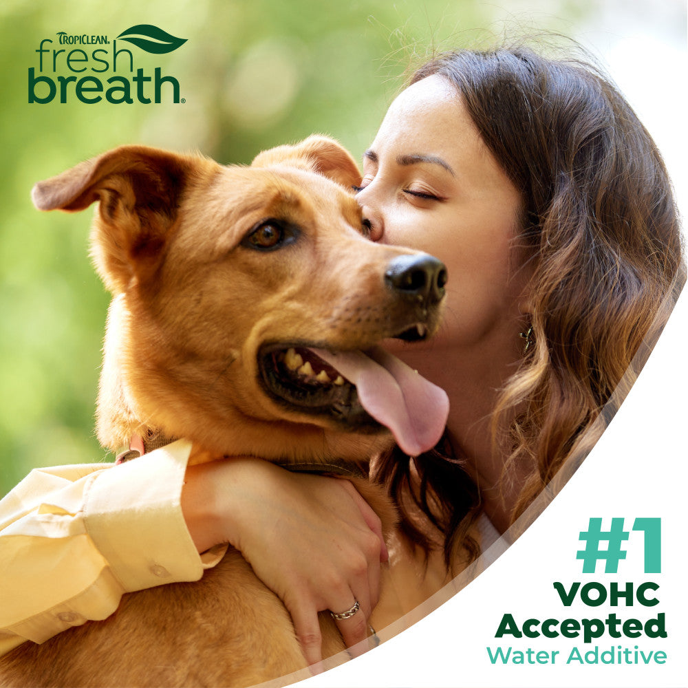 Woman hugging a dog with TropiClean Fresh Breath branding and text about VOHC acceptance.