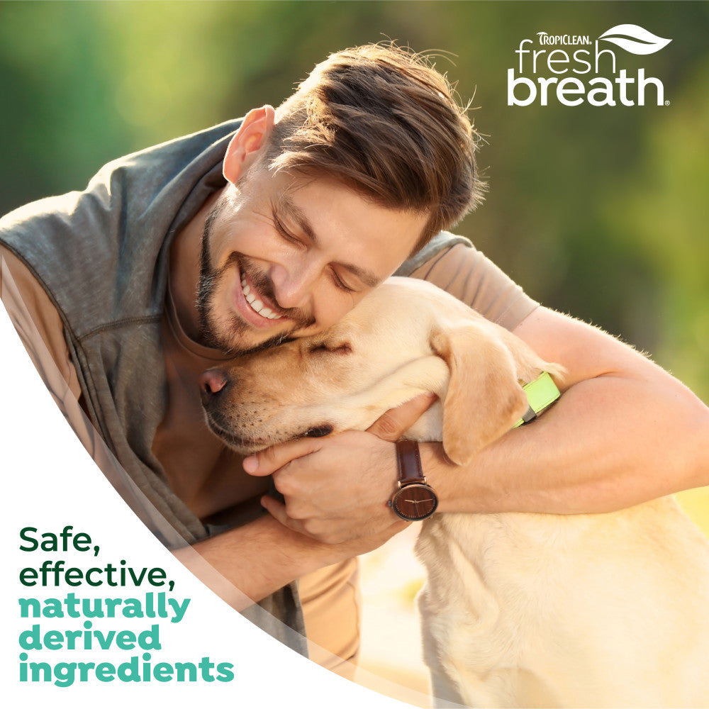 Man hugging a dog with TropiClean Fresh Breath branding and product description text.
