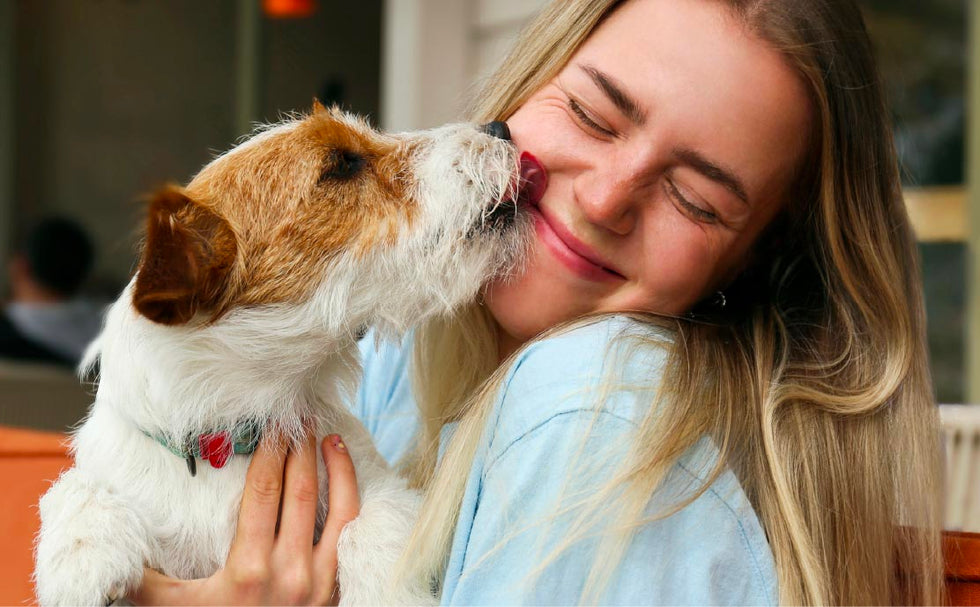 TropiClean Dental Solutions for Dogs and Cats. Dog licking a woman's face both looking happy.