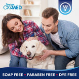 TropiClean OxyMed Ear Cleaner for Dogs and Cats. Couple with a dog on a couch, Tropiclean OxyMed branding visible
