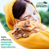 Woman in a yellow hoodie with an orange cat, featuring TropiClean Fresh Breath branding.