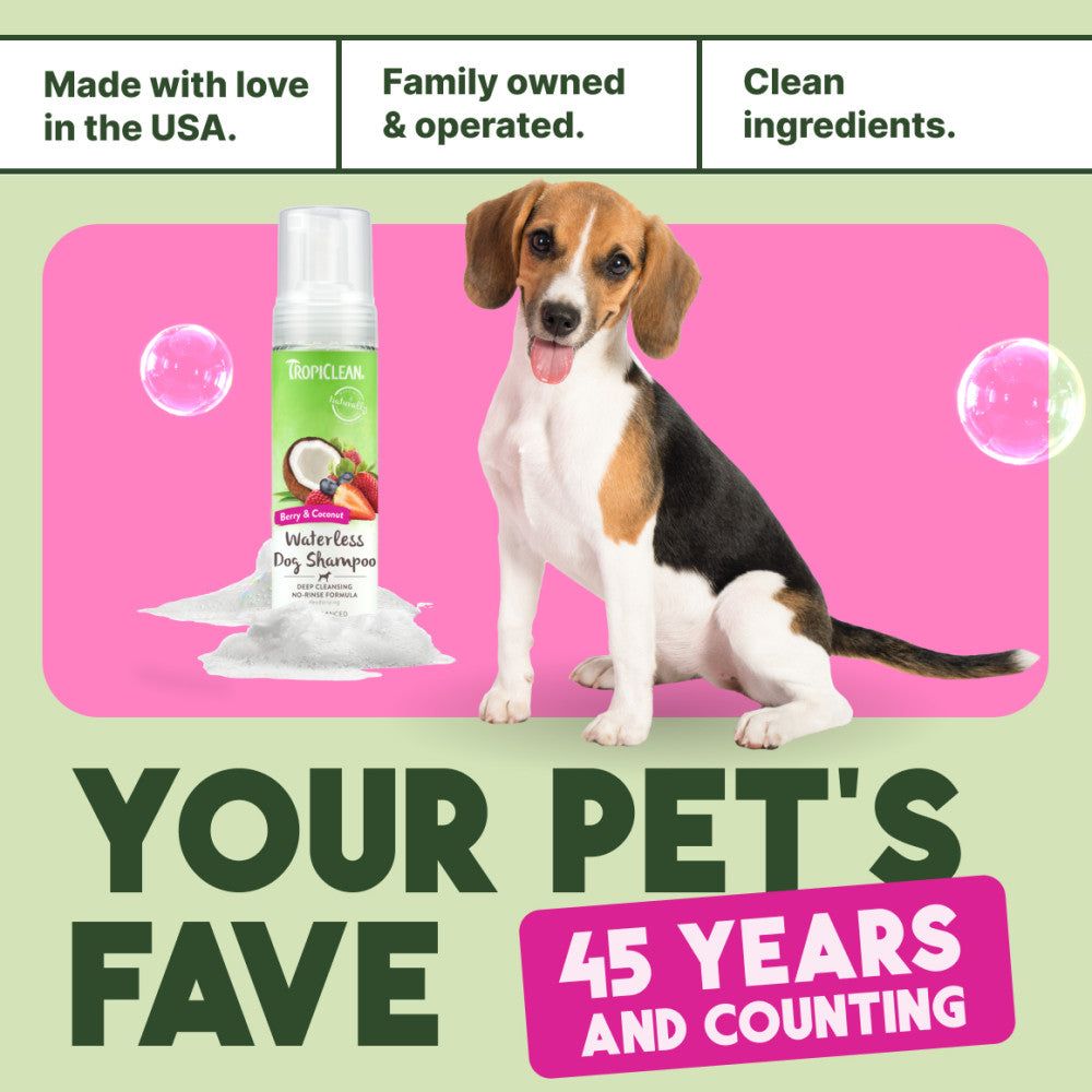 TropiClean Deep Cleansing Waterless Dog Shampoo bottle with a dog on a pink and green background, featuring text about family ownership and product features.