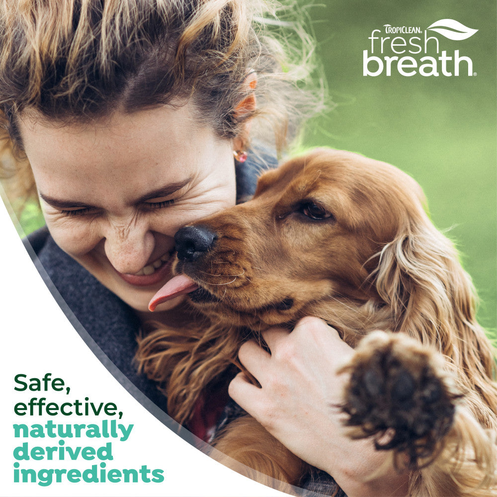 Woman hugging a dog with TropiClean Fresh Breath branding and product benefits text.