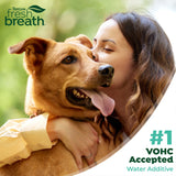 Woman hugging a dog with 'TropiClean Fresh Breath' branding and text about VOHC acceptance.