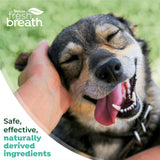 Dog with open mouth, tongue out, being petted by a hand on grass, with 'TropiClean Fresh Breath' branding.