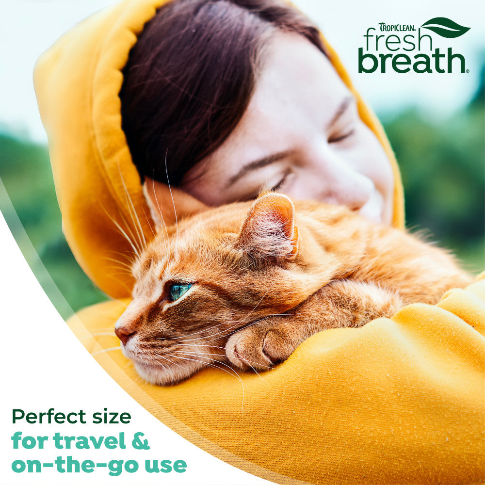 Woman in a yellow hoodie with an orange cat, featuring TropiClean Fresh Breath branding.