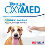 TropiClean OxyMed all-purpose wipes with a dog and hand holding a wipe