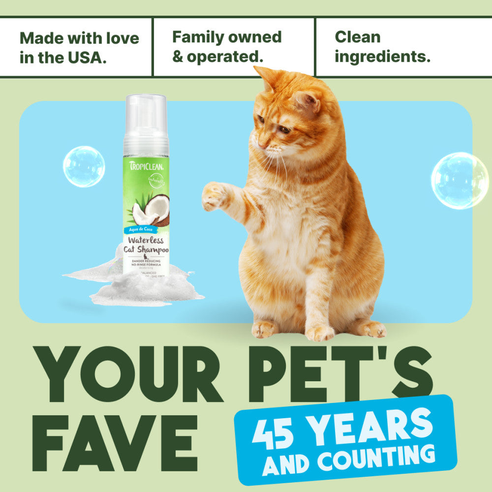 Cat with a bottle of TropiClean Dander Reducing Waterless Cat Shampoo with text about family ownership and product features.