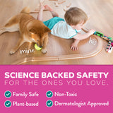 Child playing with a toy train set on a wooden floor next to a dog, with text about product safety features.