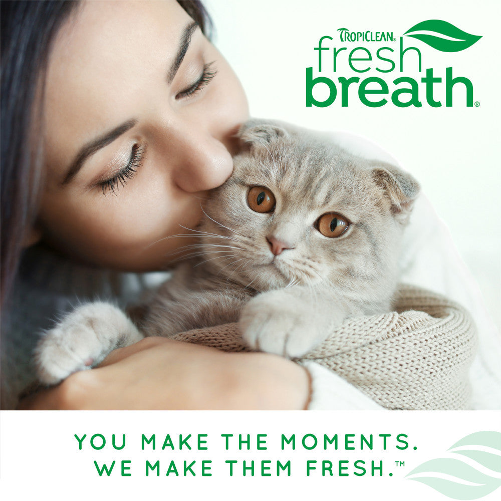 Woman kissing a cat with TropiClean Fresh Breath logo and tagline.