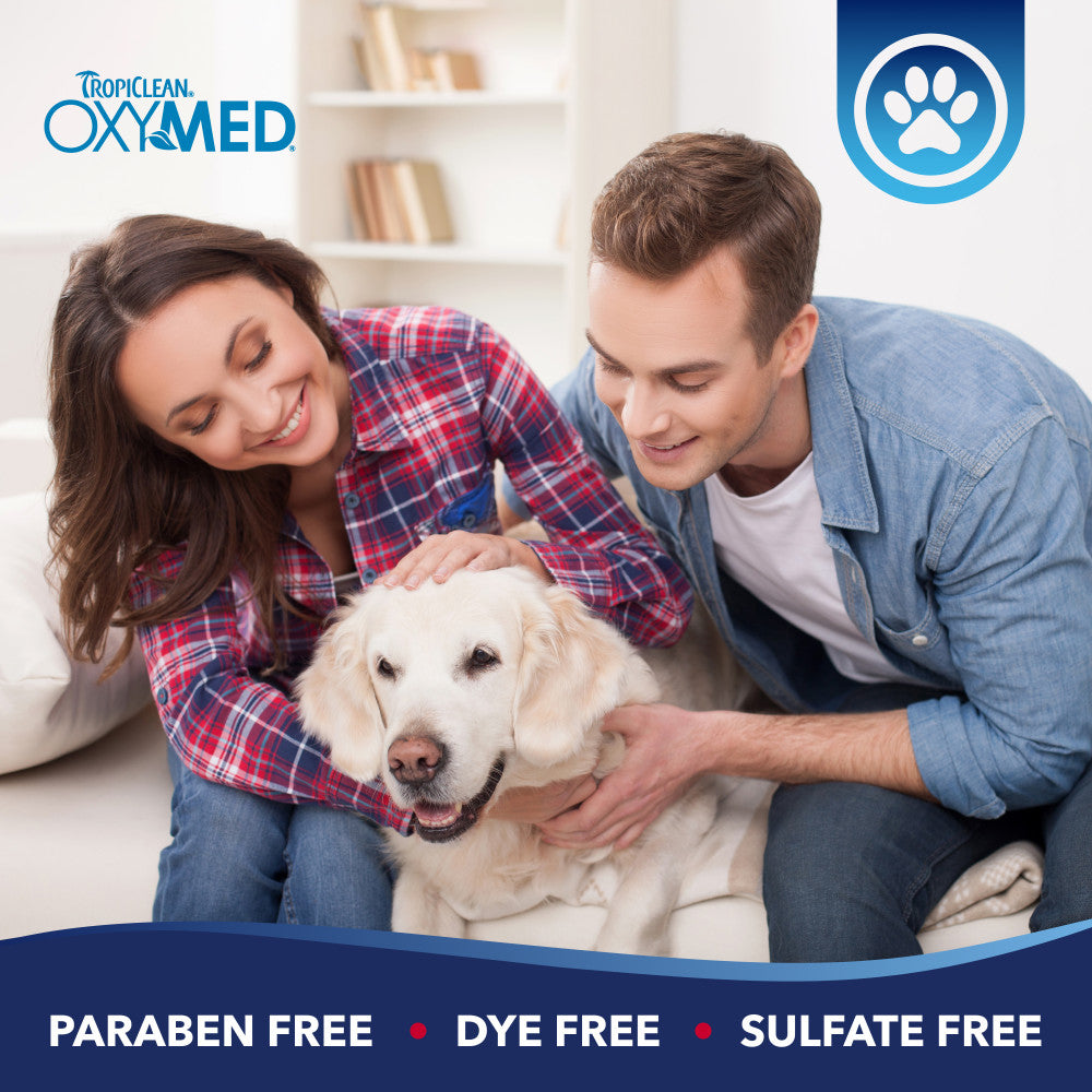 Couple with a dog on a couch, Tropiclean OxyMed branding visible